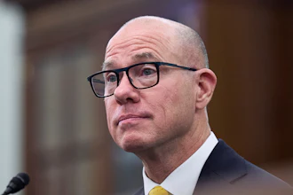 Bald professional in black-rimmed glasses and yellow tie looking thoughtful
