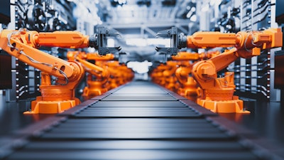 Industrial robotic arms positioned symmetrically on automated manufacturing assembly line.
