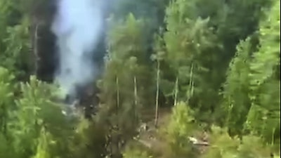 In this photo taken from video released by Russia Emergency Situations Ministry press service on Thursday, July 24, 2025, smoke rises from the crash site of a Russian An-24 passenger plane of the Siberia-based Angara Airlines about 15 kilometers (9 miles) south of Tynda, Far Eastern Amur region of Russia.