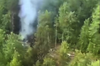 In this photo taken from video released by Russia Emergency Situations Ministry press service on Thursday, July 24, 2025, smoke rises from the crash site of a Russian An-24 passenger plane of the Siberia-based Angara Airlines about 15 kilometers (9 miles) south of Tynda, Far Eastern Amur region of Russia.