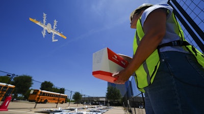 Masslie Arias, of DoorDash, prepares to load a delivery package on a hovering drone Thursday, July 31, 2025, in Frisco, Texas.