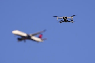 A drone hovers in airspace outside the safety perimeter surrounding St. Louis Lambert International Airport as an airliner approaches for a landing on March 10, 2025.