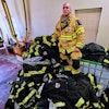 Firefighter Christopher Harrington stands next to the station's old turnout gear, while wearing recently issued non-PFAS turnout gear, at Fire Station 4 on July 3, 2025, in East Providence, R.I.