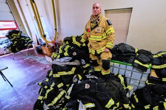Firefighter Christopher Harrington stands next to the station's old turnout gear, while wearing recently issued non-PFAS turnout gear, at Fire Station 4 on July 3, 2025, in East Providence, R.I.