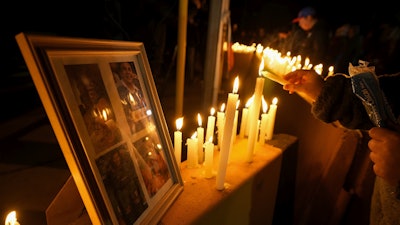 A person lights a candle during a vigil in front of El Teniente copper mine, operated by Codelco, where a cave-in killed six workers, halting operations in Rancagua, Chile, Saturday, Aug. 2, 2025.