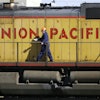 A maintenance worker walks past a locomotive in the Union Pacific Railroad fueling yard in north Denver, Oct. 18, 2006.