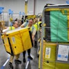 Amazon employees load packages on carts at Amazon's DAX7 delivery station, July 16, 2024, South Gate, Calif.