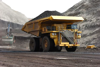 Large yellow mining dump truck loaded with coal in rocky quarry landscape