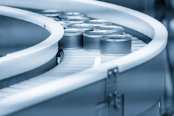 Tin cans moving on curved conveyor belt.