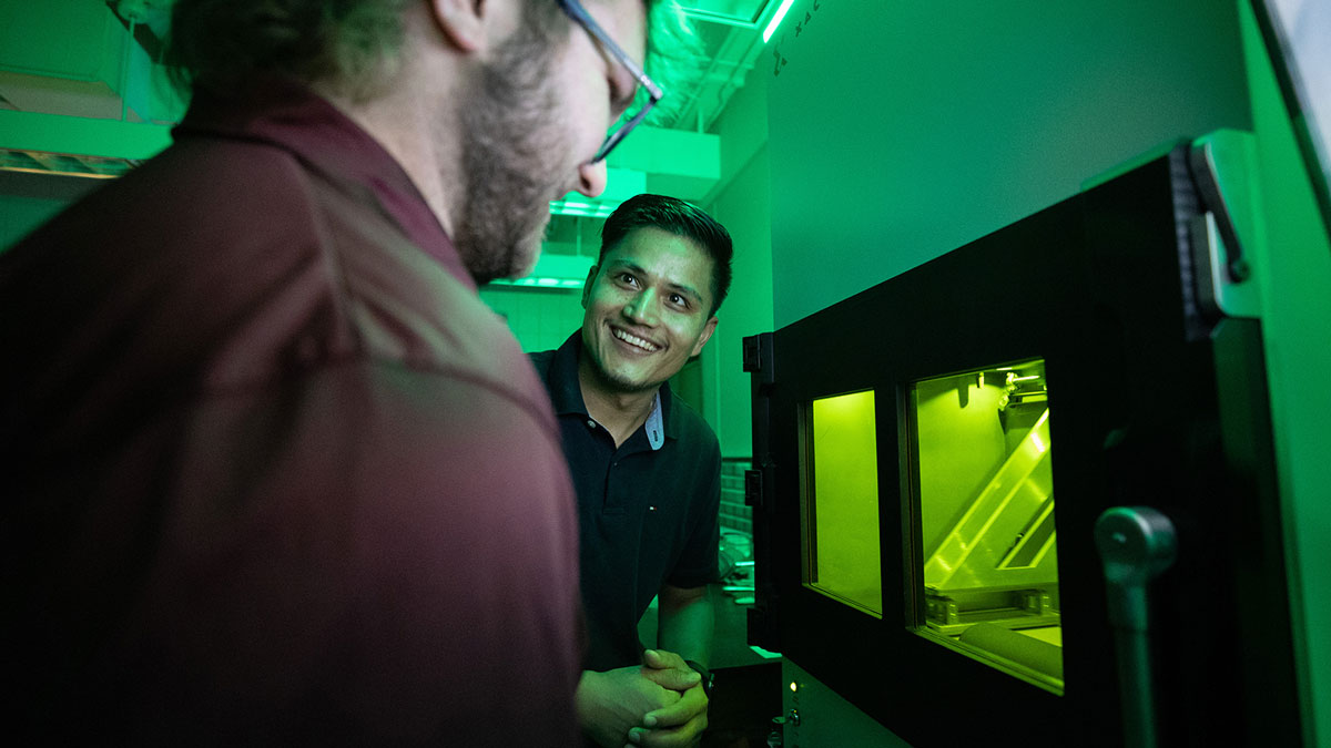 Mechanical engineering master&rsquo;s students Reese Rodely (left) and Kamal Kunwar discuss what they are observing in SIU Carbondale&rsquo;s 3D metal printer.