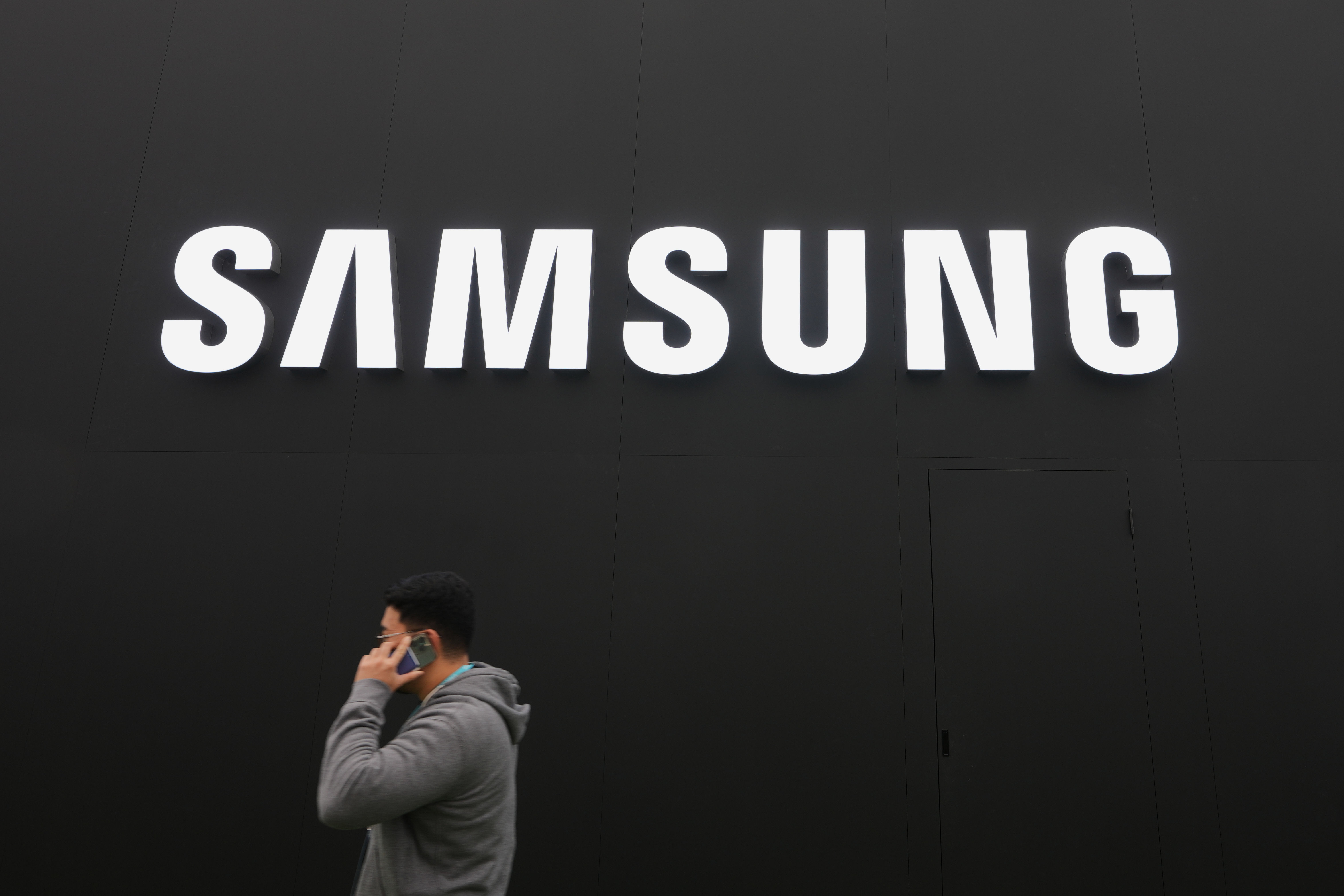 A person walks by a logo of Samsung Electronics at an exhibition hall for the Asia-Pacific Economic Cooperation (APEC) in Gyeongju, South Korea, Thursday, Oct. 30, 2025.