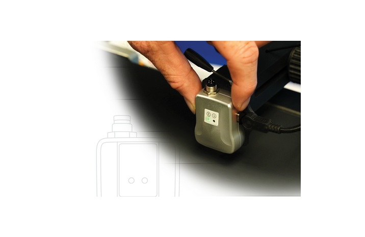 Hand adjusting small electronic device with green indicator light
