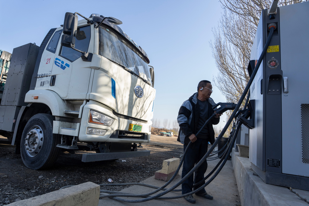 A driver charges his electric truck at a charging station on the outskirts of Beijing, on Nov. 14, 2025.