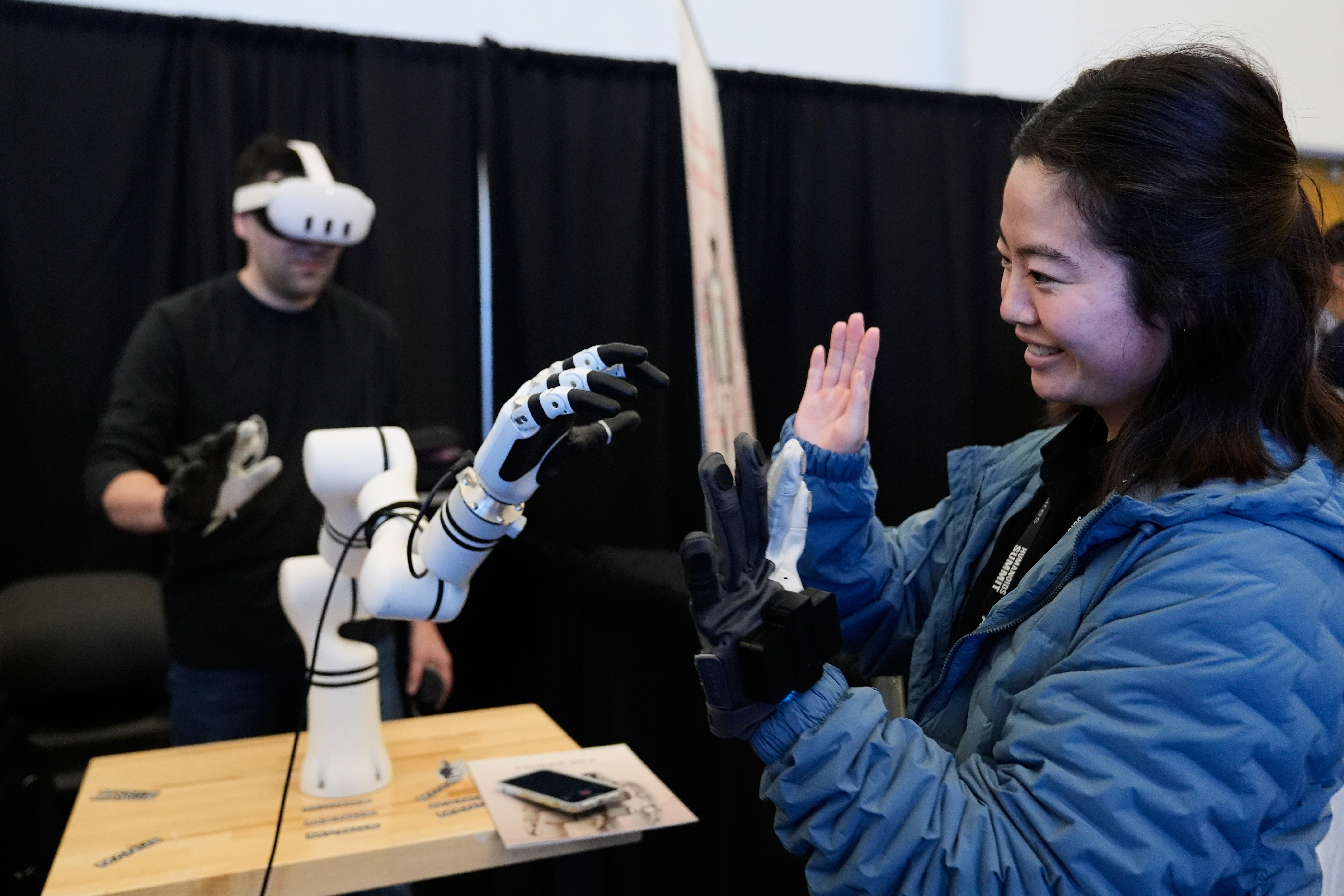 Yuka Iwashita, right, interacts with a robotic hand at the Alt-Bionics table during the Humanoids Summit, Thursday, Dec. 11, 2025, in Mountain View, Calif.