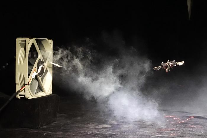 Computer fan generating smoke with drone flying nearby in dark experimental setting