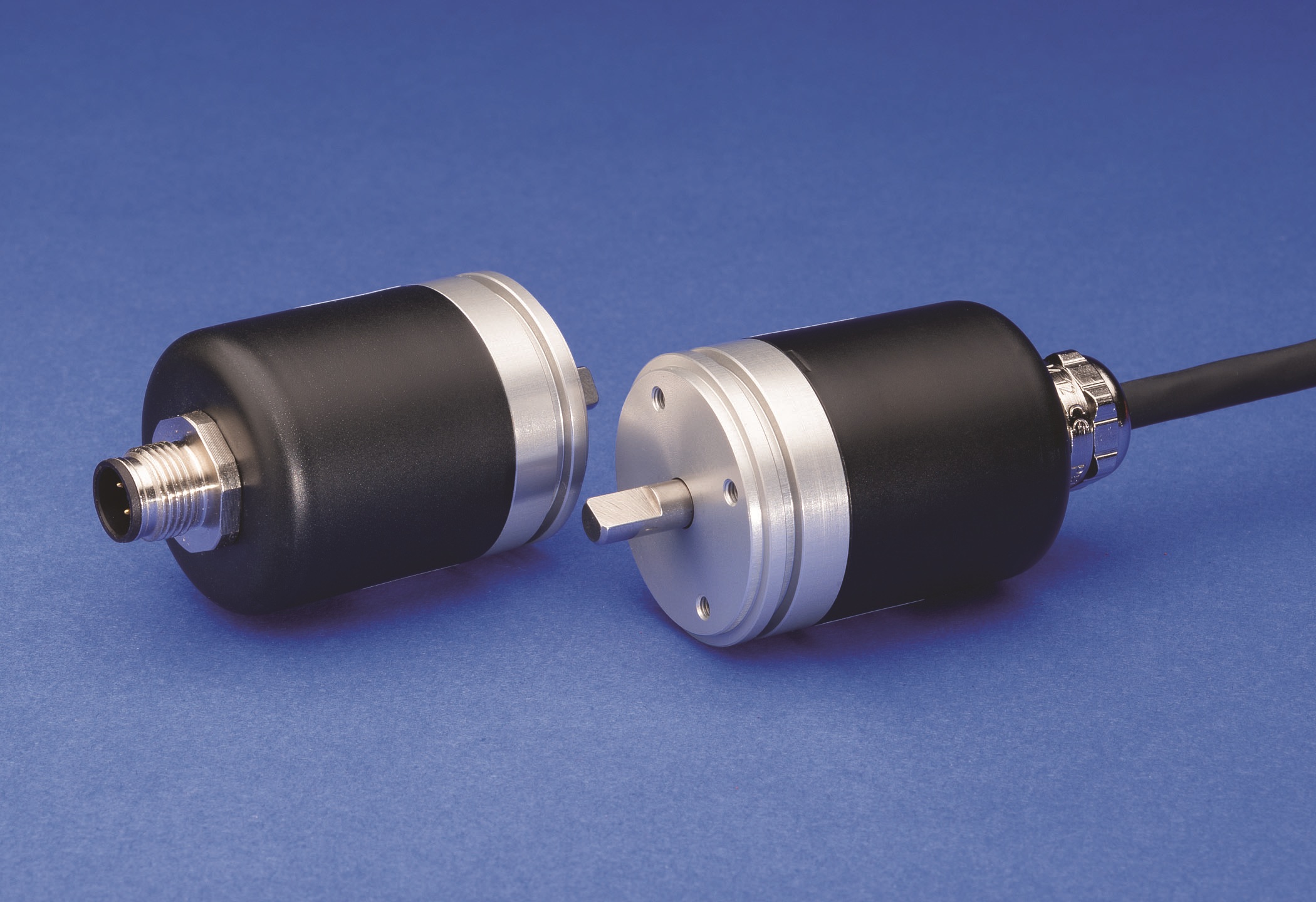 Two black and silver cylindrical industrial rotary sensors or encoders