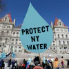 A man carries a sign before a rally opposing the Constitution Pipeline outside the state Capitol in Albany, N.Y., April 5, 2016.
