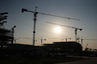 Construction site with tower cranes silhouetted against dawn sky
