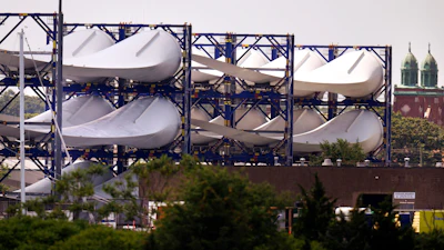 Giant wind turbine blades for the Vineyard Winds project are stacked on racks in the harbor, July 11, 2023, in New Bedford, Mass.
