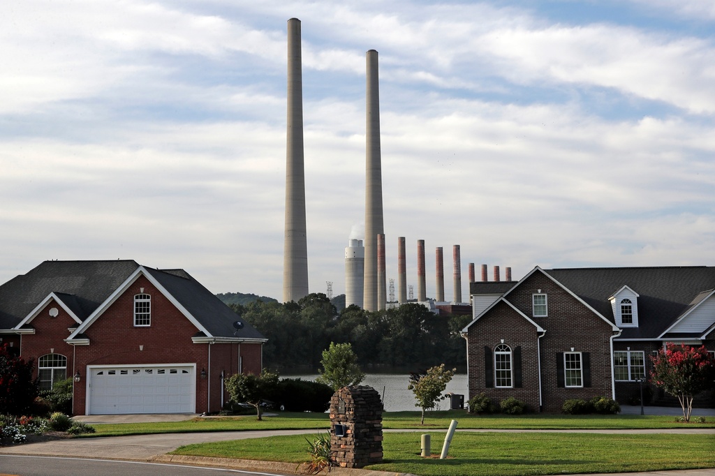 The Kingston Fossil Plant smokestacks rise above the trees behind homes in Kingston, Tenn, Aug. 7, 2019.