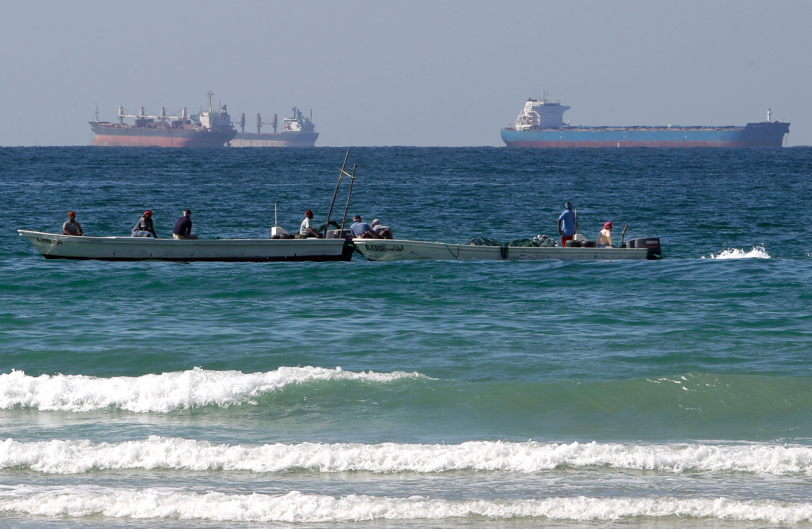 Fishermen work in front of oil tankers south of the Strait of Hormuz, Jan. 19, 2012, off Ras Al Khaimah, United Arab Emirates.