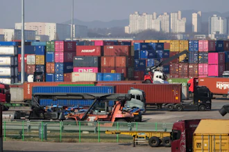 Trucks run by containers at the Uiwang ICD Terminal in Uiwang, South Korea, Thursday, March 12, 2026.