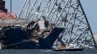 A boat moves past the bow of the container ship Dali prior to the detonation of explosive charges to bring down sections of the collapsed Francis Scott Key Bridge resting on the Dali, May 13, 2024, in Baltimore.