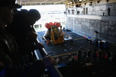 Crew members of the USS John P. Murtha join NASA and U.S. Navy officials as they gather in front of the Artemis II capsule in the bay area before docking at Naval Base San Diego, Saturday, April 11, 2026, in San Diego.