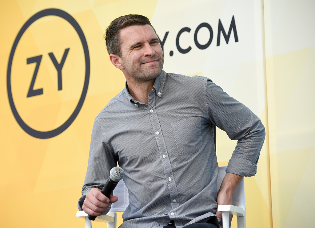 Man in gray button-up shirt speaking at a Zynga corporate event with microphone