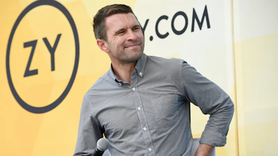 Man in gray button-up shirt speaking at a Zynga corporate event with microphone