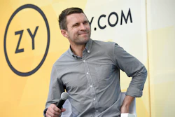 Man in gray button-up shirt speaking at a Zynga corporate event with microphone