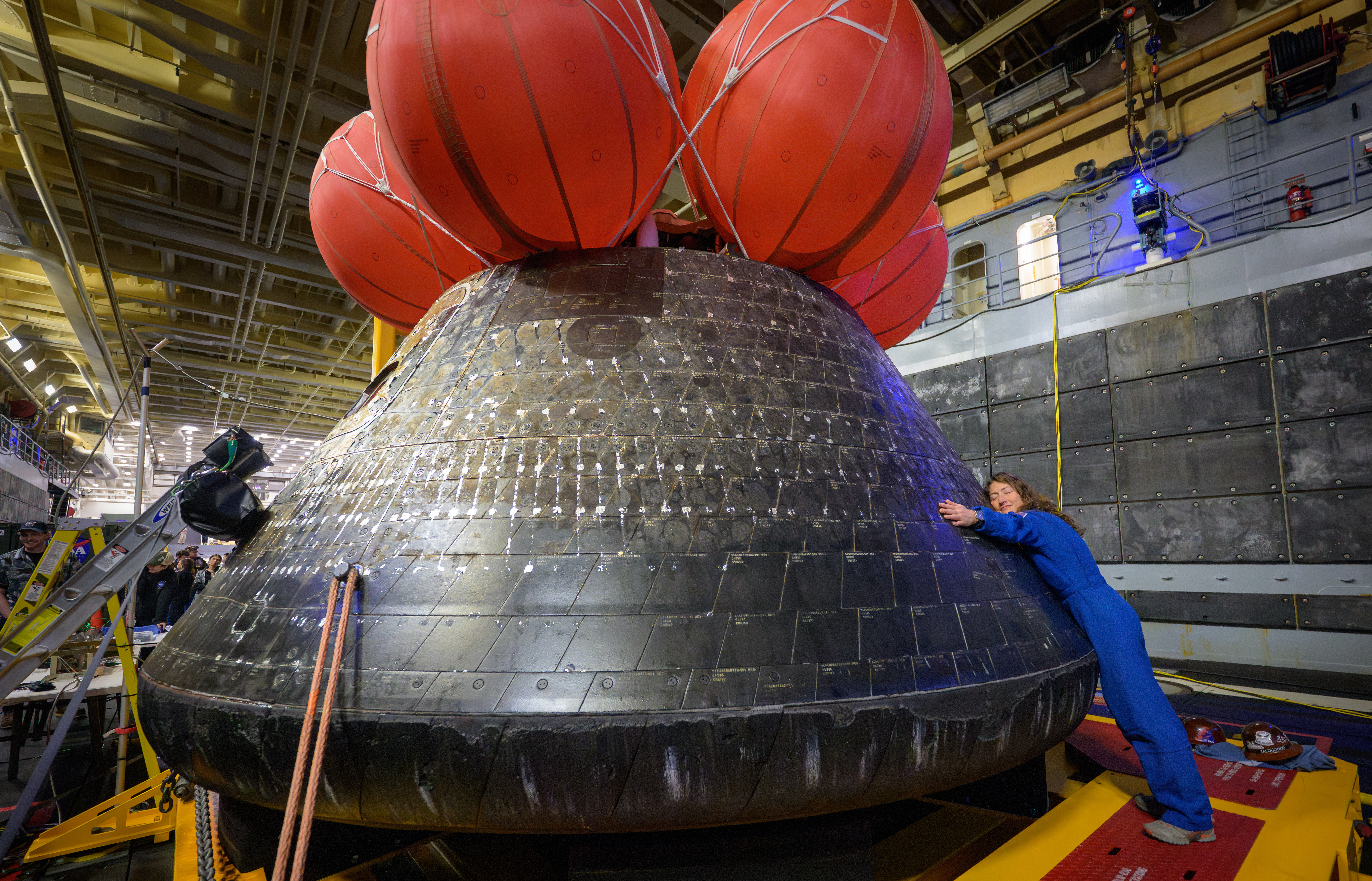 In this photo provided by NASA, Artemis II mission specialist and NASA astronaut Christina Koch hugs the Orion spacecraft aboard the USS John P. Murtha, Saturday, April 11, 2026, off the coast of California.