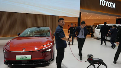 A visitor and his robotic dog stand near to the Toyota BZ7 EV model showcased at the Auto China 2026, in Beijing, Friday, April 24, 2026.