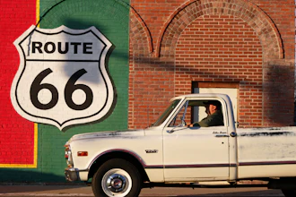 Vintage truck parked in front of Route 66 mural on brick wall