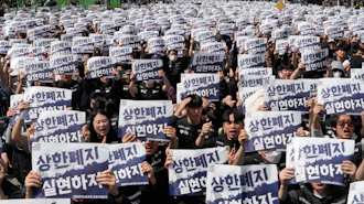 Members of the Samsung Electronics labor union hold up their cards during a rally demanding higher bonuses at its computer chip complex in Pyeongtaek, South Korea, Thursday, April 23, 2026. The letters read 'Remove the bonuses caps.'