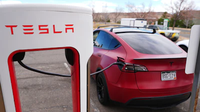 A motorist sits in a Tesla Model 3 at a Tesla charging station Friday, March 13, 2026, in Lakewood, Colo., in Denver.