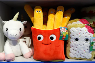 Colorful plush toys on shelf including unicorn, smiling french fries container, and cupcake character