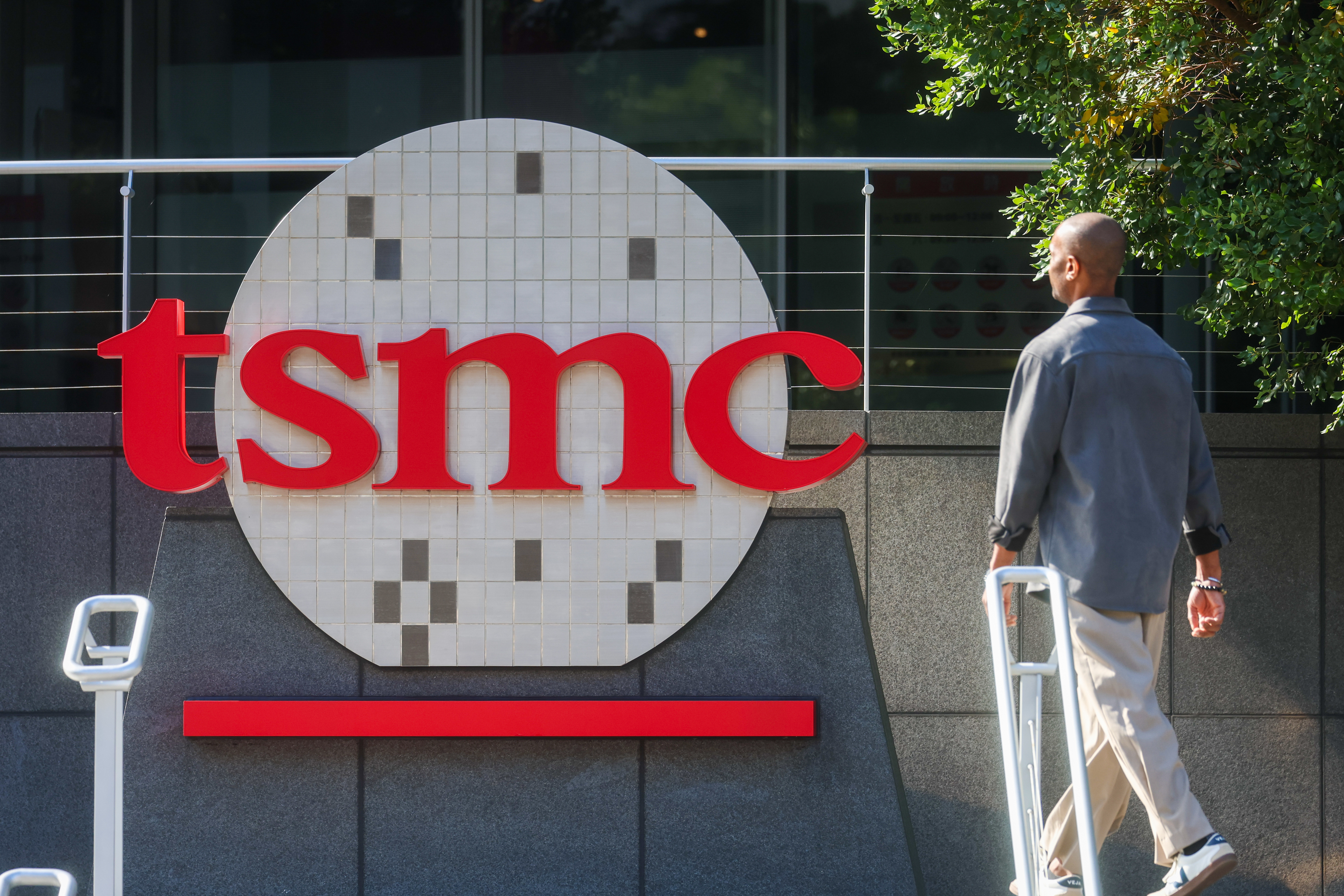 A worker walks past the logo of TSMC or Taiwan Semiconductor Manufacturing Corp., a Taiwanese multinational semiconductor contract manufacturing and design company, in Hsinchu, Taiwan, on Thursday, Jan. 29, 2026.