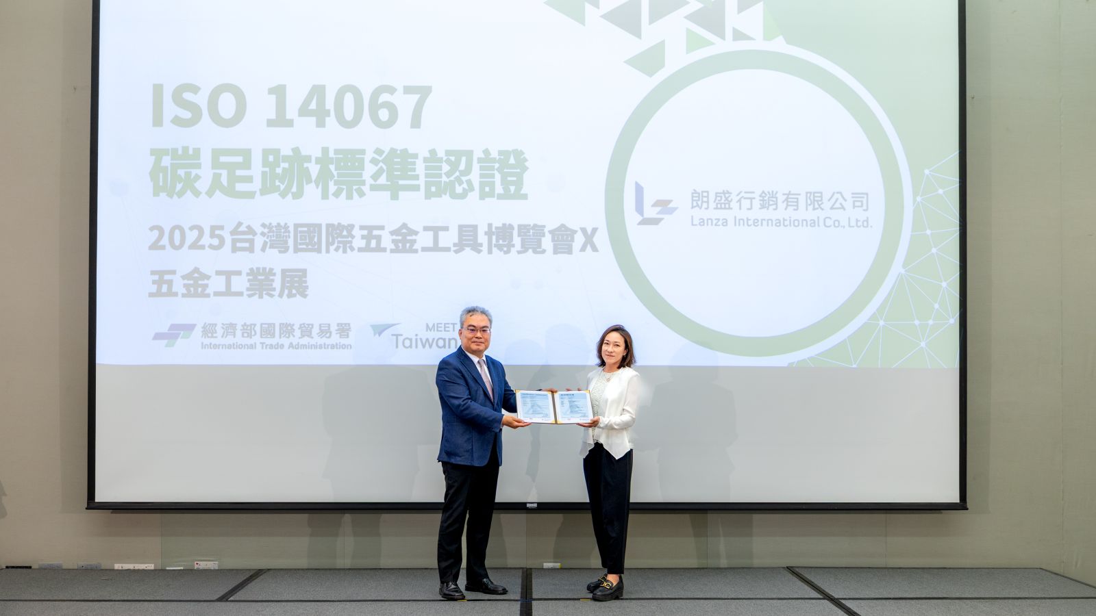 The official presentation ceremony for the ISO 14067 Carbon Footprint International Certification awarded to the 2025 TiTE x IHT. Da-Ling Shi, Deputy Economic Counselor of the International Trade Administration, Ministry of Economic Affairs (left), presents the international credential, accepted by Genny Chiang, Director of Lanza International Co., Ltd. (right).