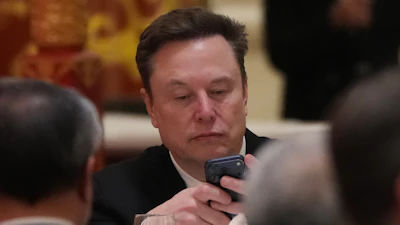 Elon Musk uses his phone during a state dinner for President Donald Trump and Chinese President Xi Jinping at the Great Hall of the People on Thursday May 14, 2026, in Beijing.