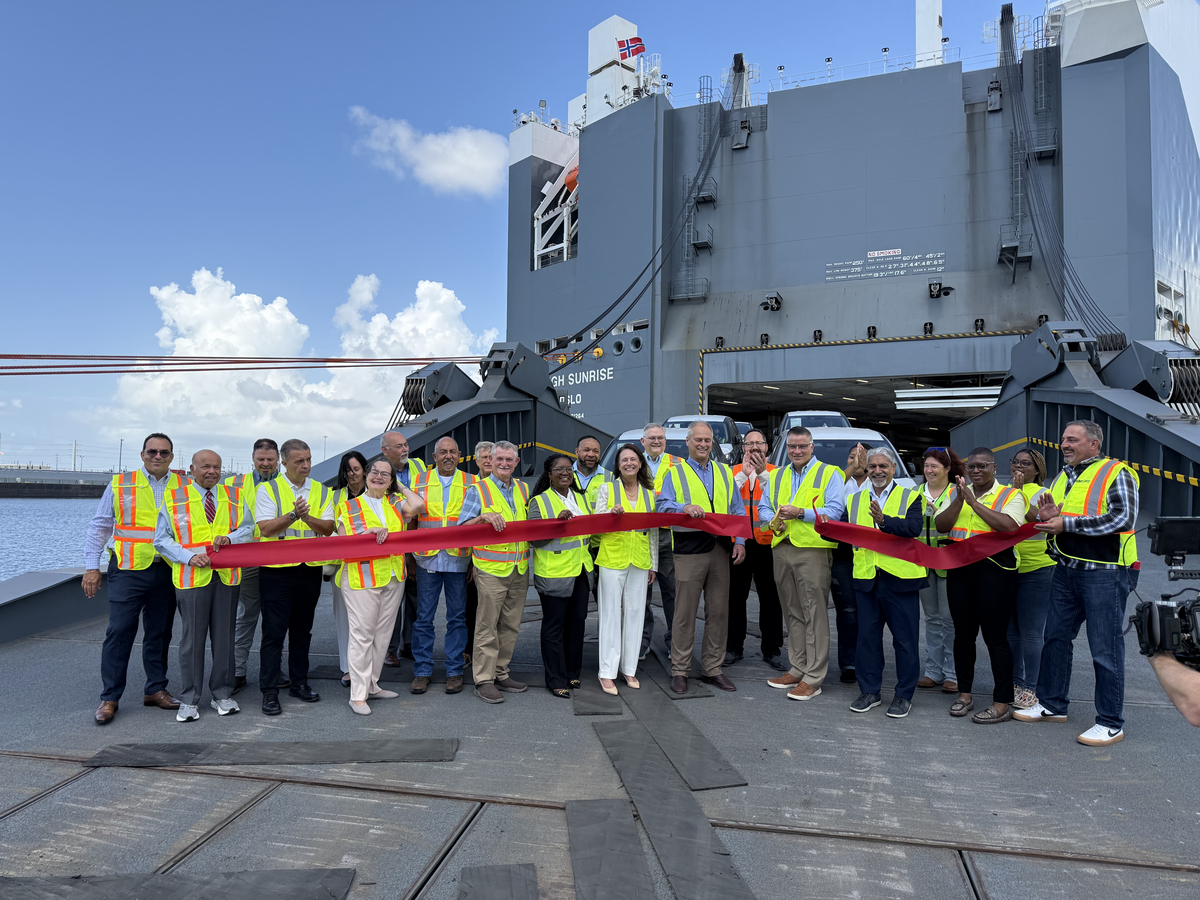 Rob Madden, Mitsubishi Motors North America, Inc., (center, with scissors) cuts the ceremonial ribbon to celebrate Port Freeport as a new U.S. distribution port for the company&rsquo;s vehicles, as new Mitsubishi vehicles roll off the H&ouml;egh Sunrise.