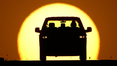 A motorist is silhouetted by the setting sun March 26, 2026, in Lenexa, Kan.