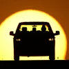 A motorist is silhouetted by the setting sun March 26, 2026, in Lenexa, Kan.