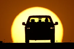 A motorist is silhouetted by the setting sun March 26, 2026, in Lenexa, Kan.