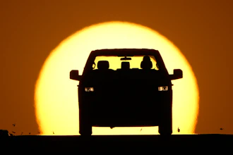 A motorist is silhouetted by the setting sun March 26, 2026, in Lenexa, Kan.