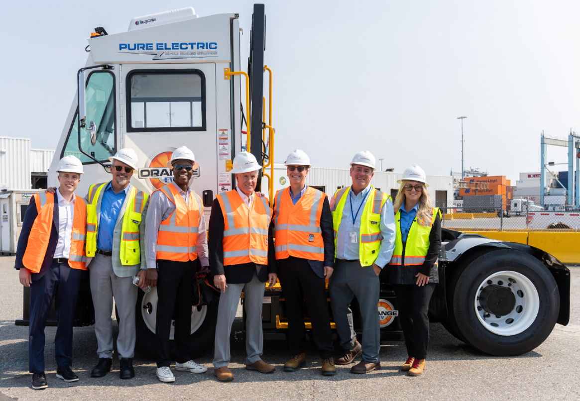 Orange EV and APM Terminals team members gather alongside an Orange EV electric terminal truck.