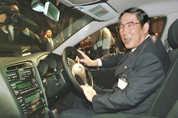 Hiroshi Okuda, then, president of Toyota Motor Corp., smiles as he sits at the steering wheel of the 'Aristo,' Toyota's remodeled sports sedan during a press conference at a Tokyo hotel, Aug. 27, 1997.