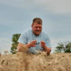 Bryce Black inspects strands of wheat at his farm in Beloit, Kan., July 29, 2026.