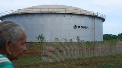 A woman walks near of a oil storage tank of Venezuela's state-run oil company, PDVSA in Cabimas, Venezuela, Tuesday, Sep. 1, 2026.