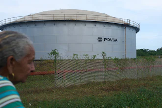 A woman walks near of a oil storage tank of Venezuela's state-run oil company, PDVSA in Cabimas, Venezuela, Tuesday, Sep. 1, 2026.